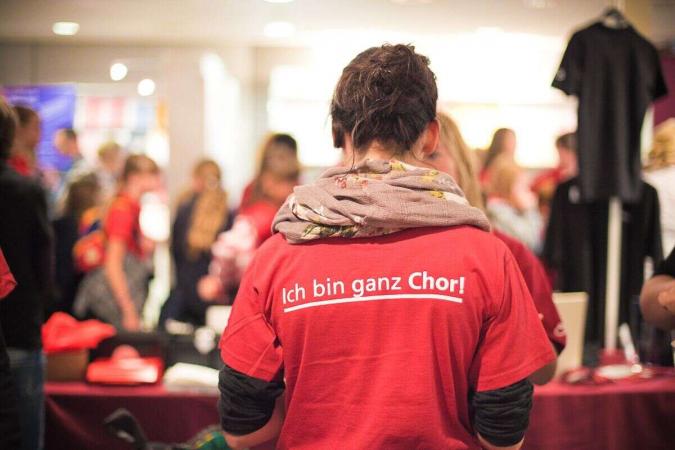 Eine Frau von hinten in einem roten Shirt mit der Aufschrift "Ich bin ganz Chor"