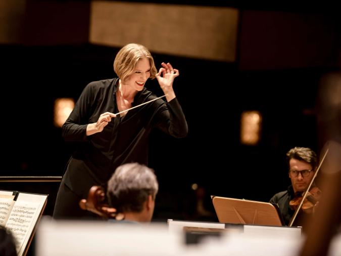 Weibliche Dirigentin dirigiert ein Orchester