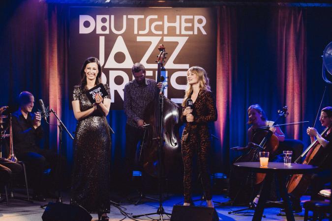 Erster Deutscher Jazzpreis 2021: Moderation und Jazzmusiker*innen im Hintergrund.