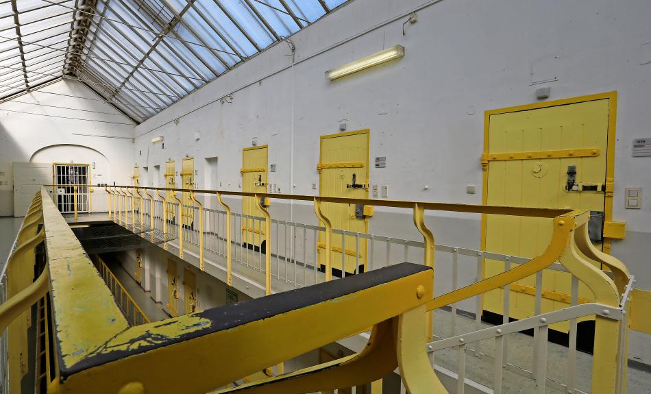 Foto eines Flurs im oberen Stockwerk eines Gefängnisses mit hellgelb gestrichenen Türen