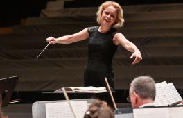 Eine blonde Frau dirigiert ein Orchester
