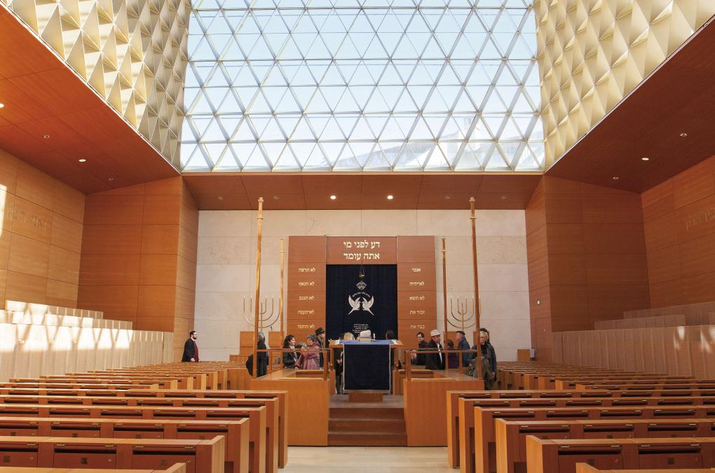 Innenansicht der Synagoge der Israelitischen Kultusgemeinde München und Oberbayern. Bänke und Wände aus Holz werden von einer großen Glaskuppel überdeckt.