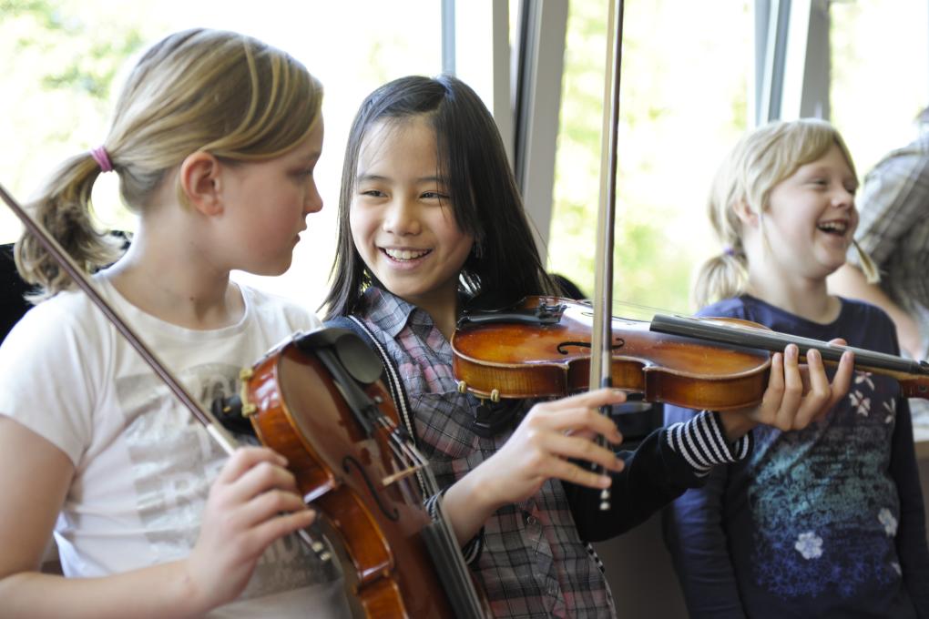 Zwei Mädchen mit Geigen vor Fensterfront